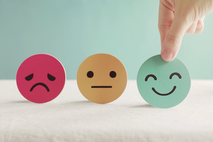 Photograph of paper icons depicting sad, neutral, and happy expressions