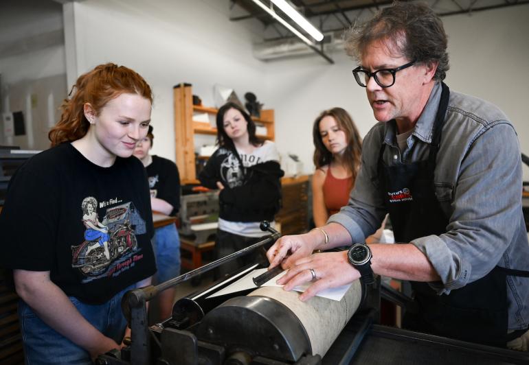 Analog Design class Professor Matt Greenwell instructs students on using a Vandercook press for letterpress.
