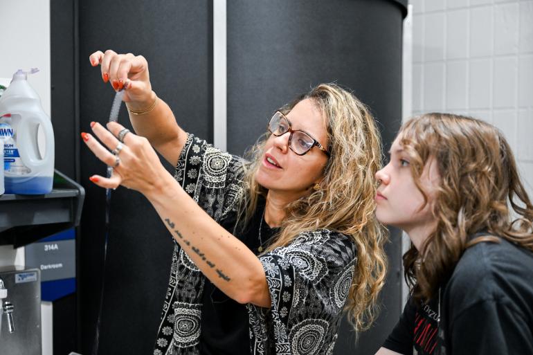 Photography I Professor Júlia Pontés reviews a film strip with a student in Photography I