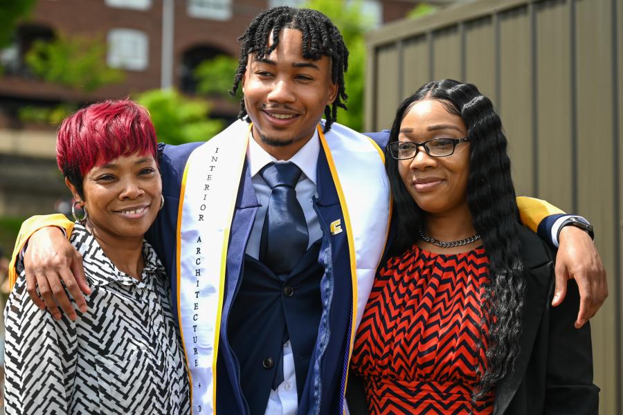 UTC undergraduate student standing in his graduation robes with his family
